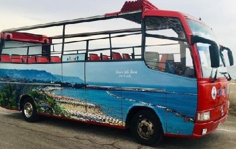 Un bus turistico scoperto percorre il lungomare